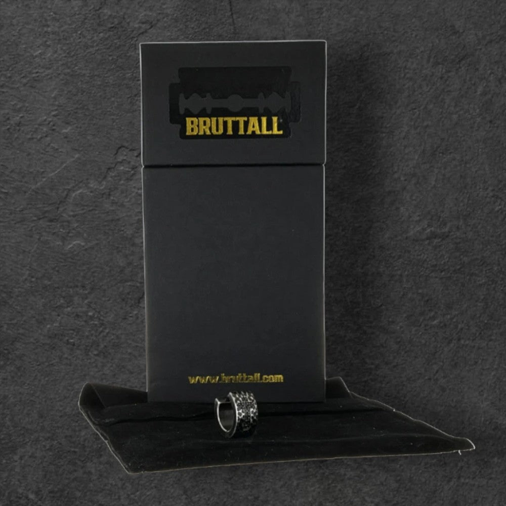 Bruttall RAW cross hoop earring with black Swarovski Zirconia in a branded black gift box on a dark textured surface.