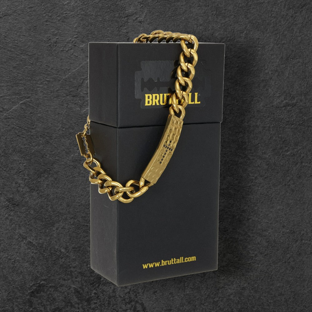 Bruttall RAW cross bracelet in matte gold plating with a chunky chain and Swarovski Zirconia detail on a black box.