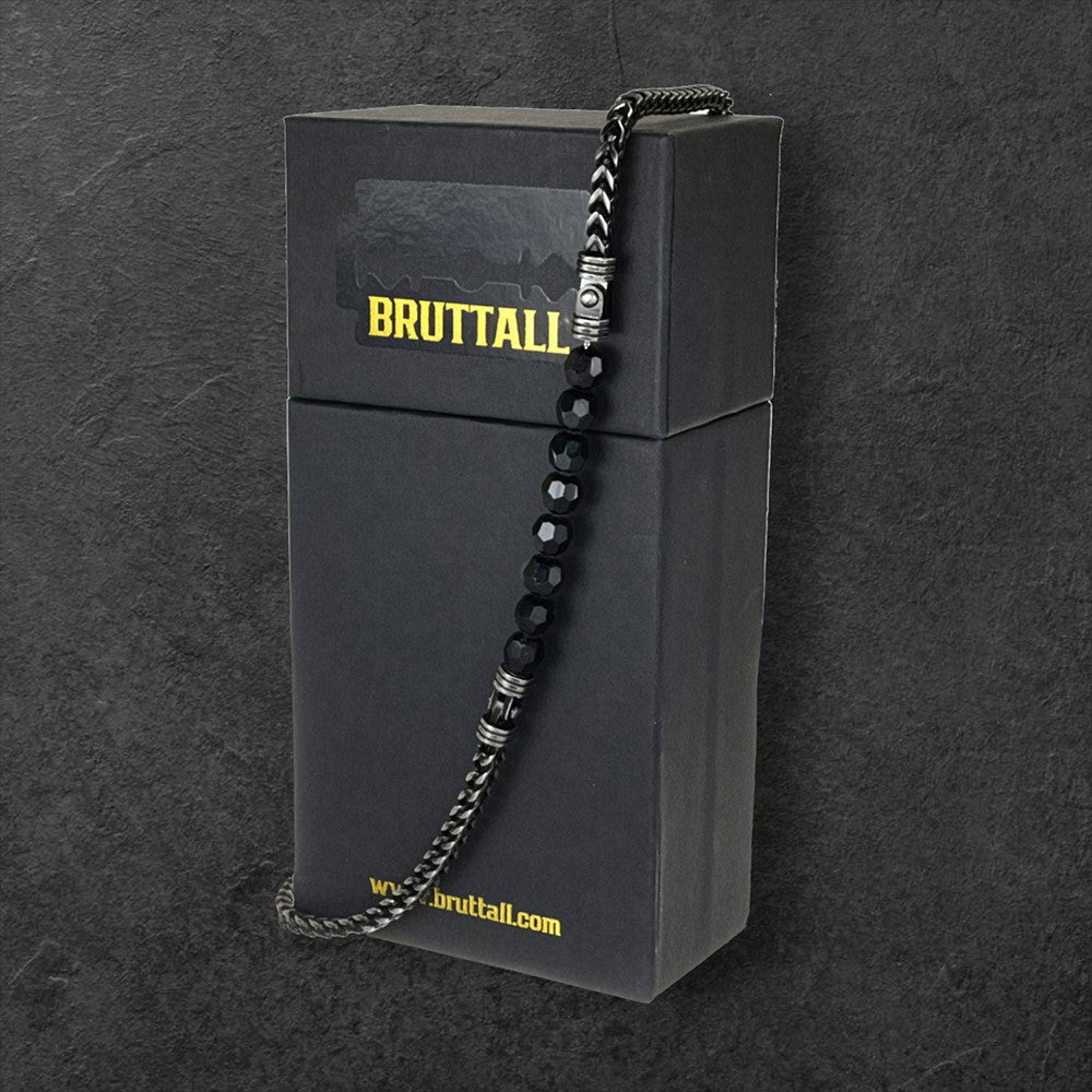 Bruttall CORE necklace featuring antique black chain links and faceted black Swarovski crystals on a black gift box.