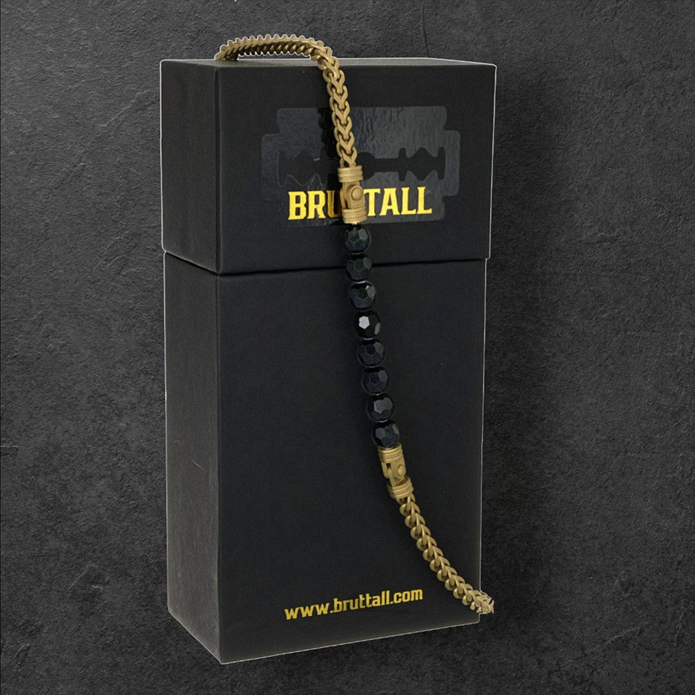 Bruttall CORE necklace featuring matte gold chain links and faceted black Swarovski crystals on a black gift box.