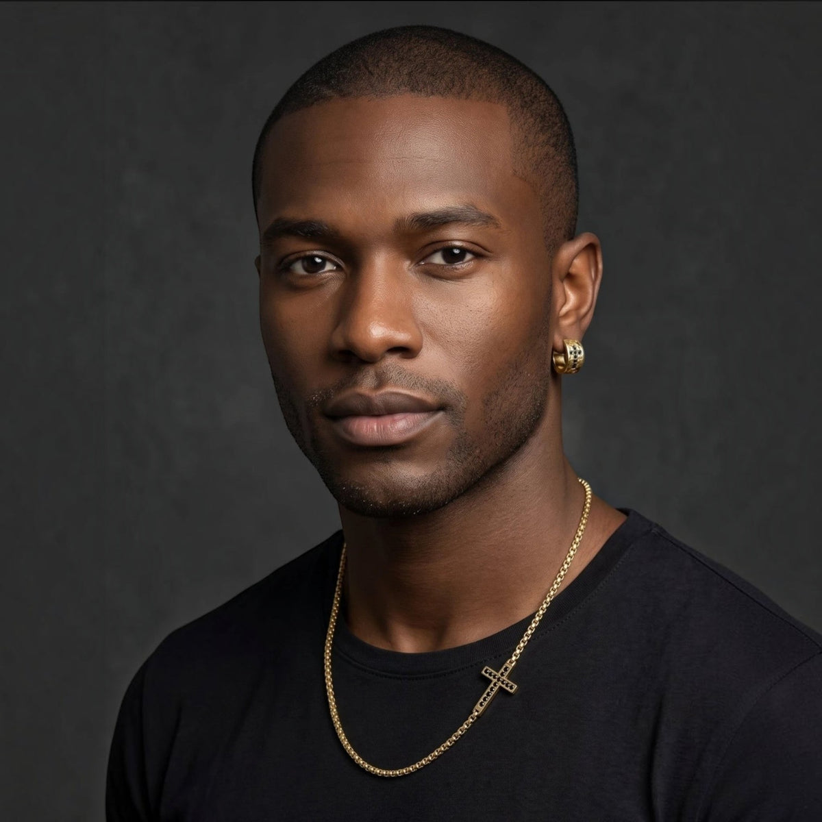 Bruttall matte gold hoop earring with black Swarovski Zirconia worn by a man with a matching cross necklace