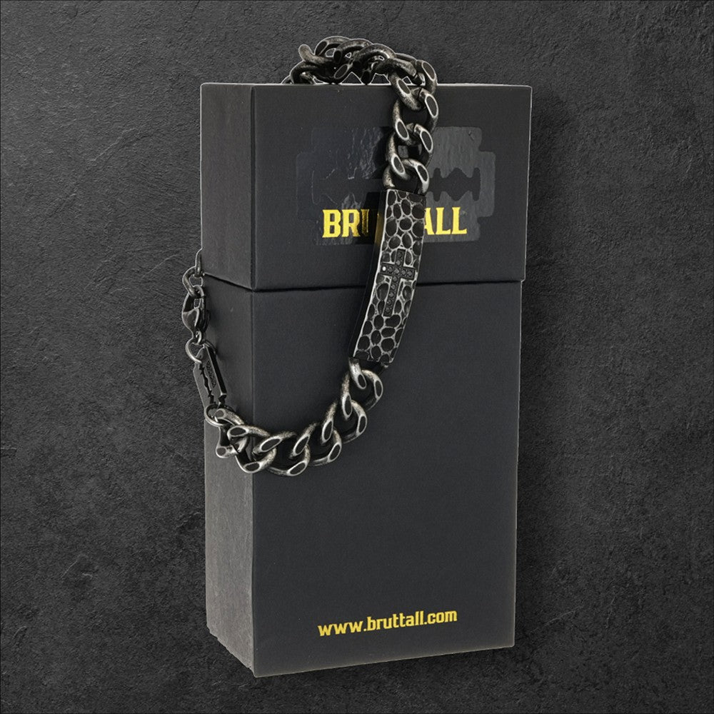 Bruttall RAW cross bracelet with antique plated finish, heavy chain links, and Swarovski Zirconia on a black box.