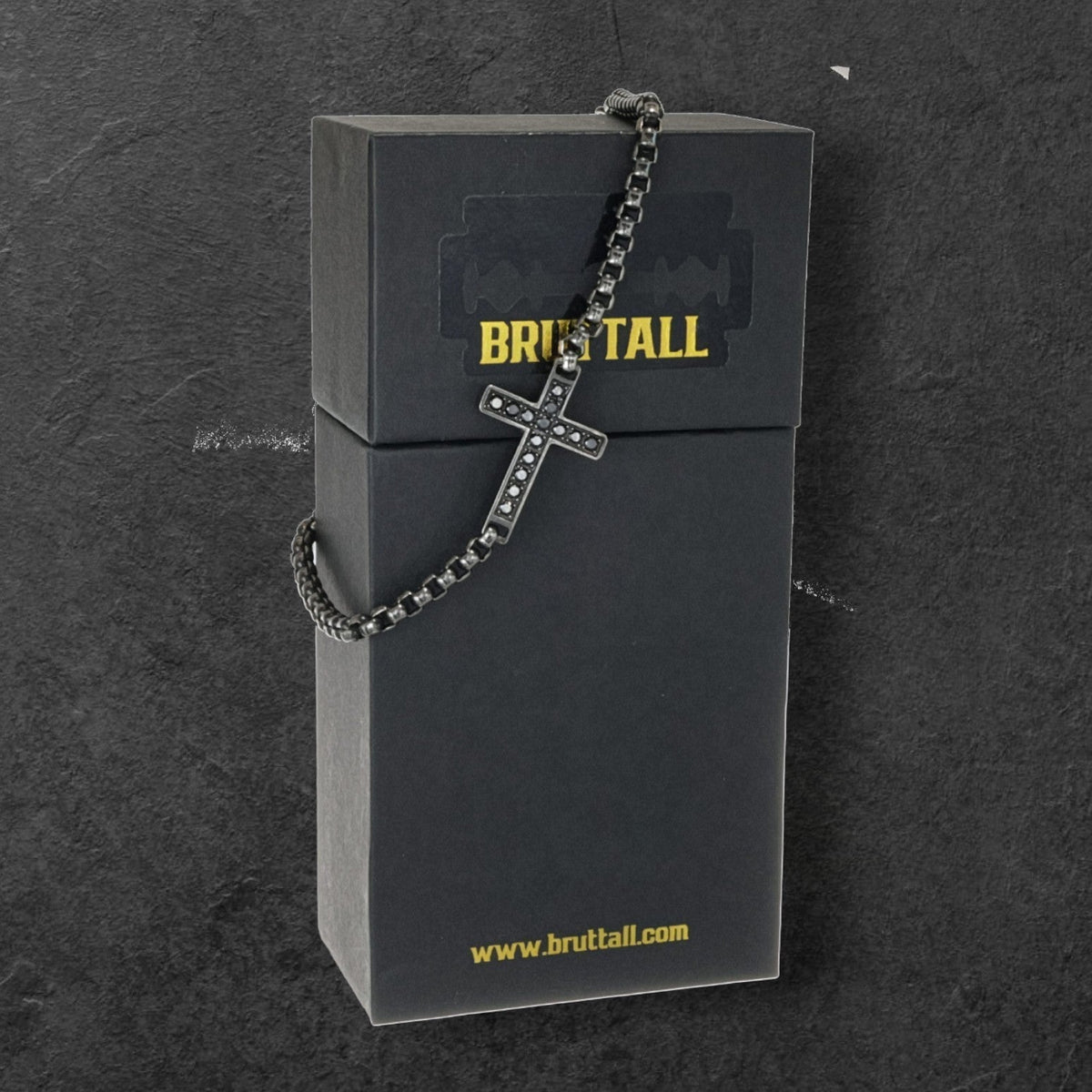 Bruttall TOWER cross bracelet in antique plating with black Swarovski Zirconia stones draped over a branded gift box.