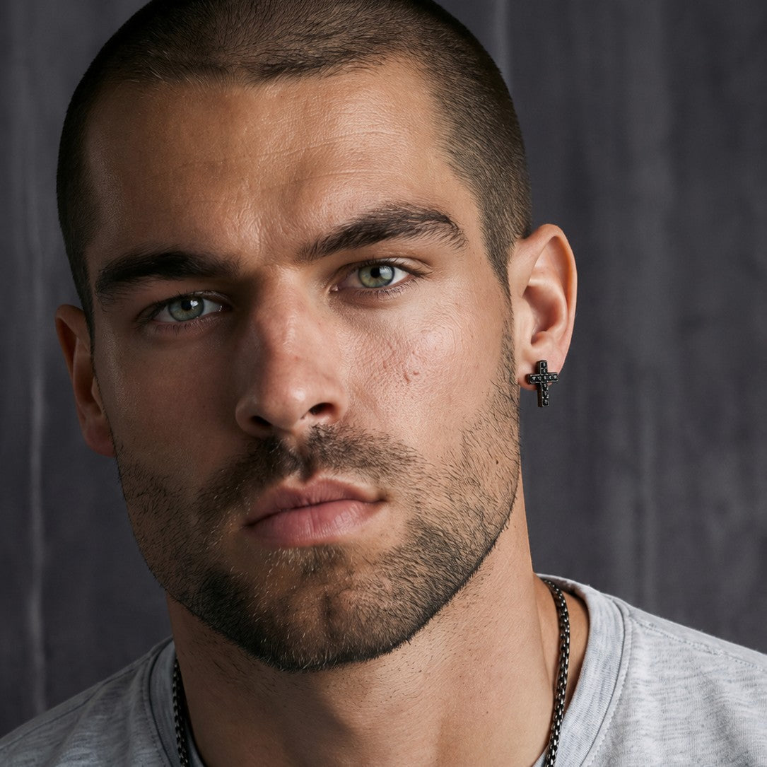 Bruttall TOWER cross earring in antique plating with Swarovski crystals worn by a man in a close-up portrait
