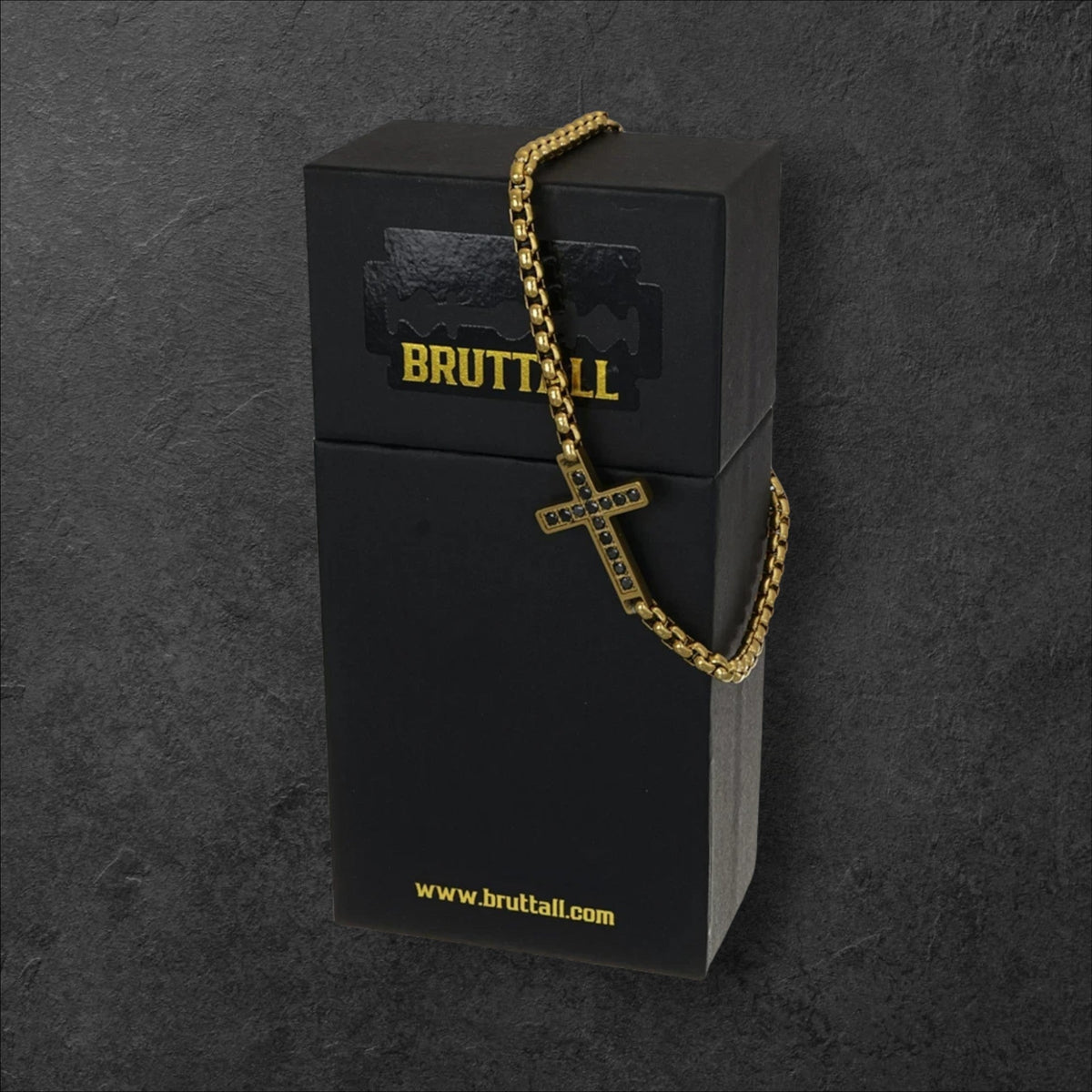 Bruttall TOWER cross bracelet in gold-plated metal with black Swarovski Zirconia stones on a black branded gift box.